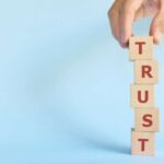 Build trust concept. Hand stacking wooden blocks with word trust.