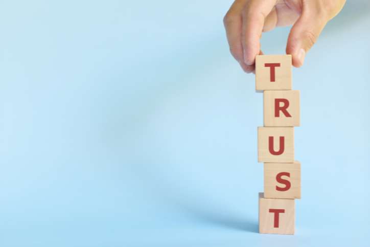 Build trust concept. Hand stacking wooden blocks with word trust.